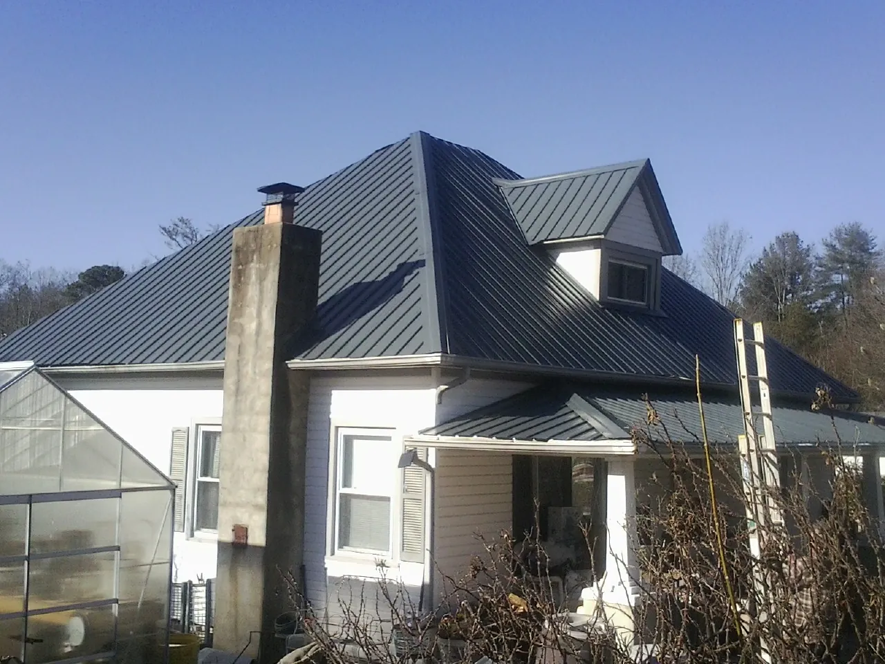 Dark blue standing seam metal roof on a white farmhouse with dormer — Slate & Tile Roof Repair by Roofing Brothers in Zanesfield
