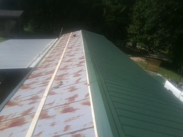Old rusted panels beside newly installed green metal roofing — Wind Damage Roof Repair by Roofing Brothers in Zanesfield