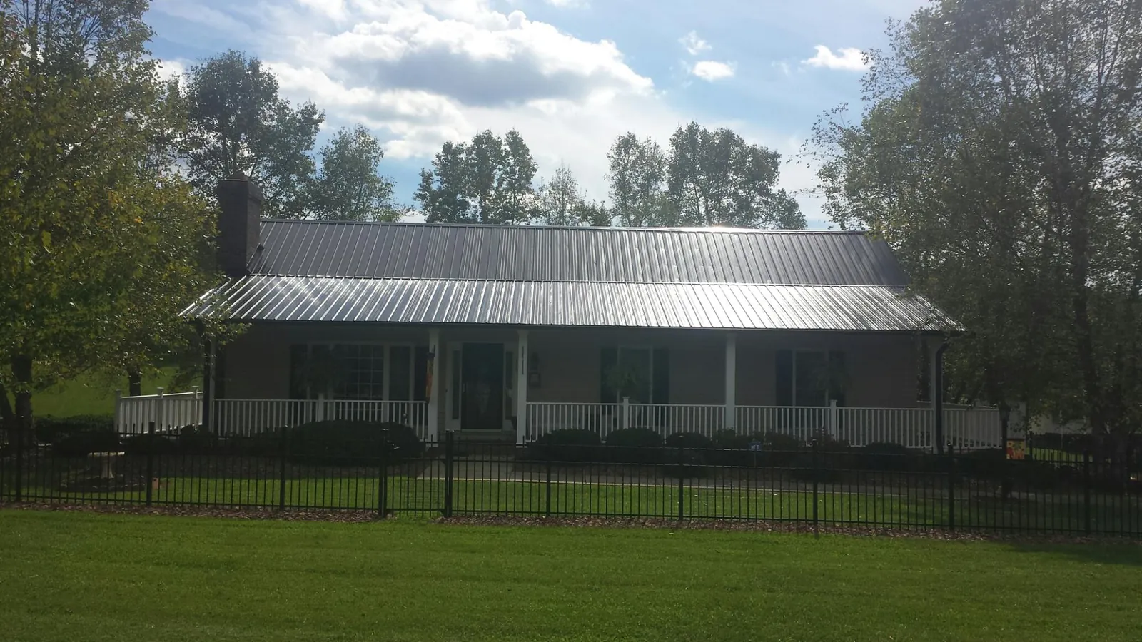 Gray metal roof on a brick ranch with a full width front porch — Gutter Guard Installation work by our crew in Zanesfield