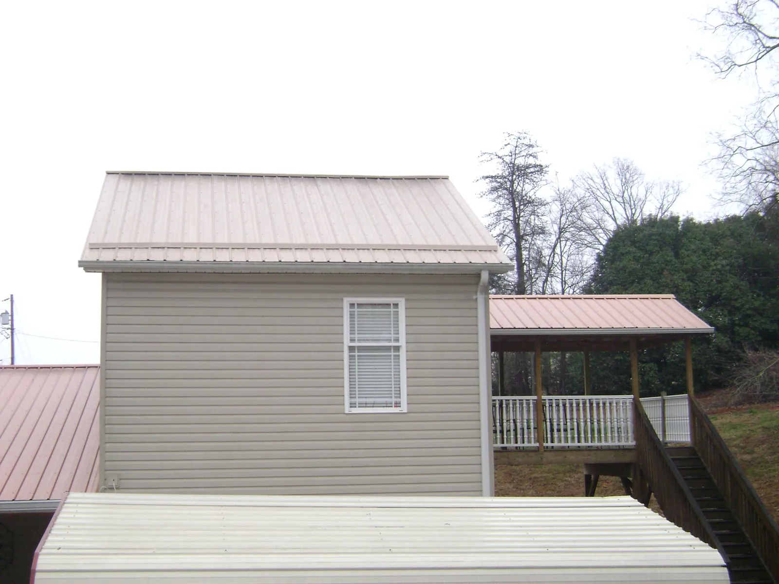 Tan metal roofs on a two story addition and attached porch, from a Roof Replacement job in Zanesfield