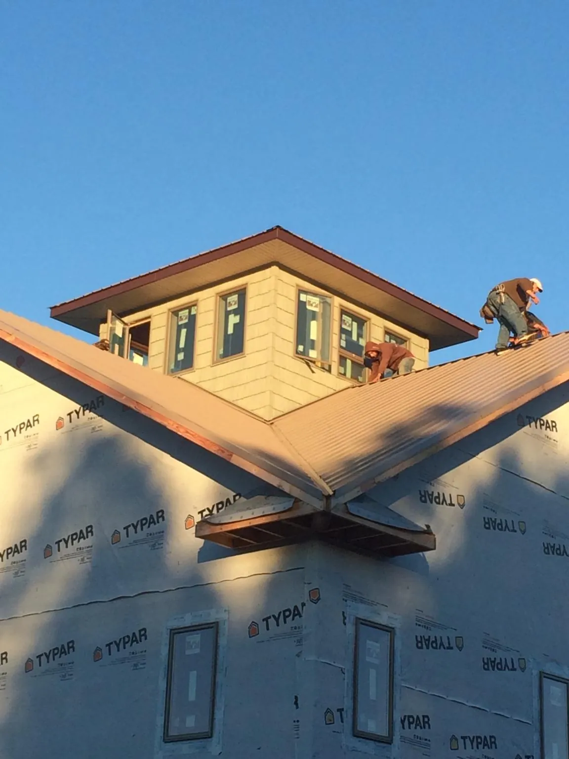 Roofers working around a rooftop cupola on a new metal roof at sunset — Roof Waterproofing in Zanesfield by Roofing Brothers